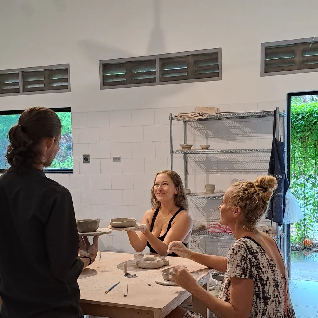 Saturday group class: a teacher and two students holding up their handbuilt bowls at Klei