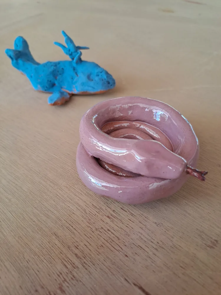 A glossy pink coiled snake and a blue whale made in a Klei class